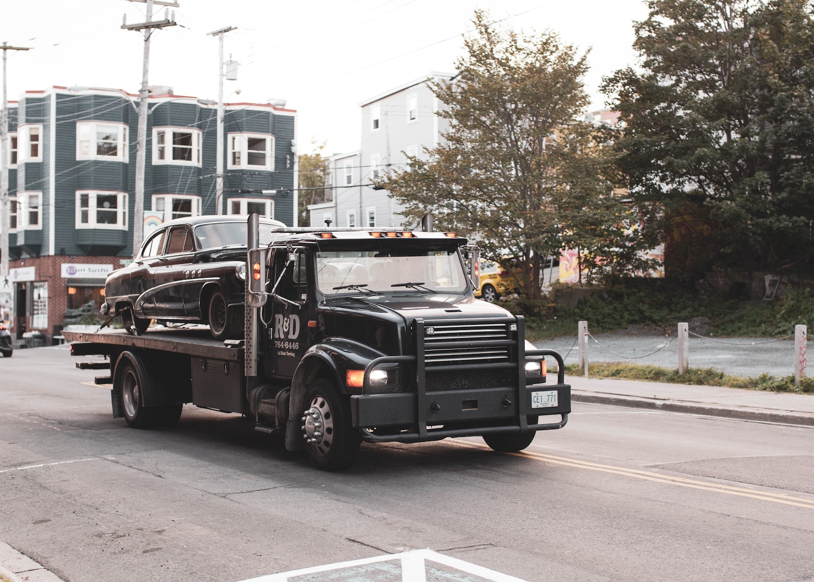 black tow truck towing vintage car